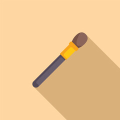 Makeup brush is lying diagonally on a light brown surface, casting a long shadow