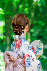 うちわを持つ浴衣を着た女性の後ろ姿