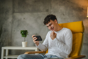 Portrait of teenage boy at home use smartphone to watch video podcast