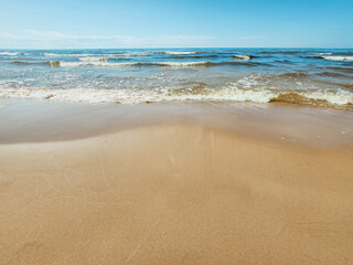 Serene Beach Horizon. Golden sands meet the gentle waves under a clear blue sky at the shoreline.