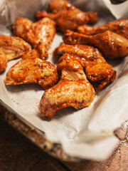 Asian style marinated chicken drumsticks and wings on cooking paper in a metal tray ready to be cooked. Fine poultry product for oven or barbecue. Simple popular traditionally meal.