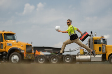 Construction man excited jump with helmet. Builder in helmet run outdoor. Worker in hardhat fast...