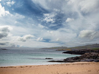 Yellow sandy beach and tropical blue ocean water and stunning cloudy sky. West coast of Ireland. Irish landscape scene. Nobody. Travel and tourism. Calm and peaceful coastline.