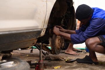 A nigerian man working on his vehicle wheels 