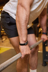 Obraz premium A man is strengthening and improving his fitness by lifting a barbell in the gym