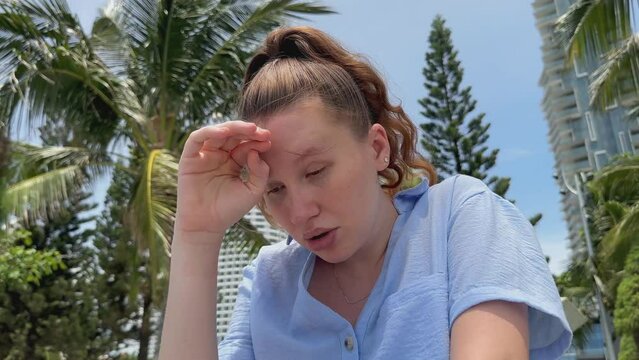 Young woman feeling bad, suffering from sunstroke at sea, beach at summer