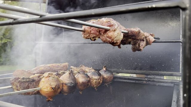 A typical gaucho barbecue on a metal grill, with onions, flank steak and sirloin on skewers at the outdoor in a beautiful sunny summer day