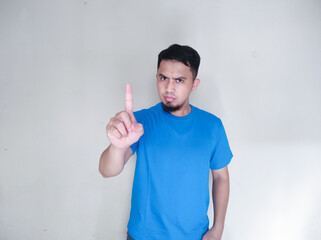 Young serious and confident asian man showing stop, one finger gesture, taboo sign, standing over...