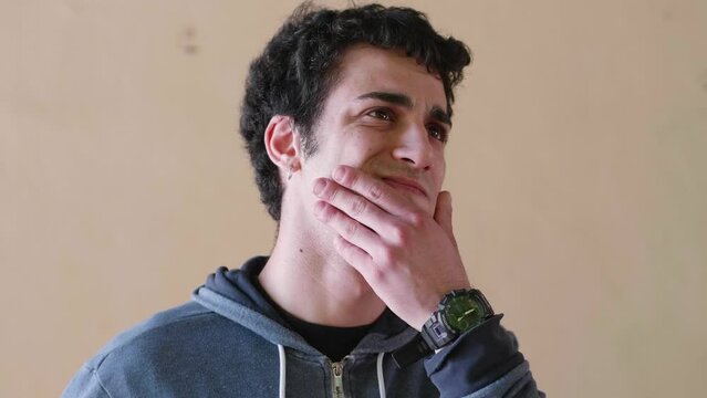 A young man with short black curly hair and wearing a blue hoodie looks uncertain and contemplative, pondering over a problem he can't seem to solve.