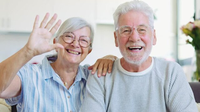 Sixty years couple, elderly parents communicates with grown up children using modern technologies makes video call, wave hands gesture of hello or goodbye sign, older generation and internet concept
