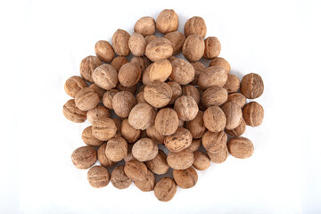 Walnut kernels in a wooden bowl and whole walnuts on table. Close up of metal pliers to open nuts with walnut nutcracker.