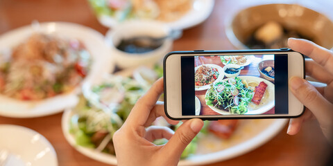 restaurant owner takes a picture of the food on the table with a smartphone to post on a website. Online food delivery, ordering service, influencer, review, social media, share, marketing, interest.