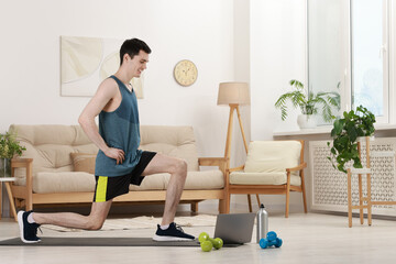 Fototapeta premium Online fitness trainer. Man doing exercise near laptop at home