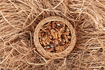 Walnut kernels in a wooden bowl and whole walnuts on table. Close up of metal pliers to open nuts with walnut nutcracker.