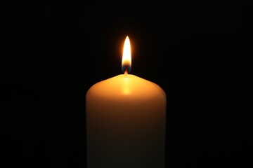 One burning church candle on black background, closeup