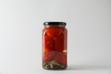 Tasty pickled tomatoes in jar on light grey background