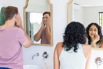 Diverse couple getting ready in front of bathroom mirrors - Powered by Adobe