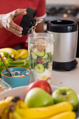 Young Asian woman preparing healthy smoothie with fresh fruits and vegetables