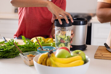 Diverse couple preparing smoothie together in kitchen