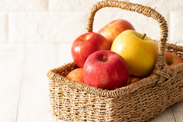 カゴいっぱいに、とれたてりんご！白レンガ背景 北海道産