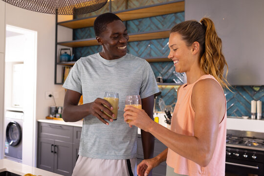 Happy diverse couple toasting smoothie, wellness and a healthy lifestyle - Powered by Adobe