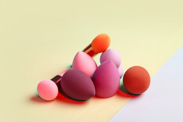 Different makeup sponges on colorful background