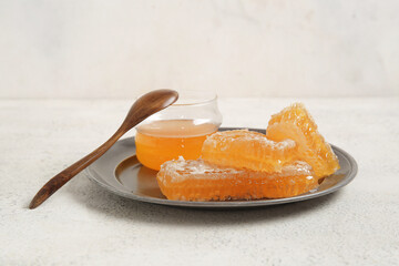 Plate with jar of sweet honey and combs on light background