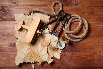 Airplane toy with travel equipment and keys on brown wooden background