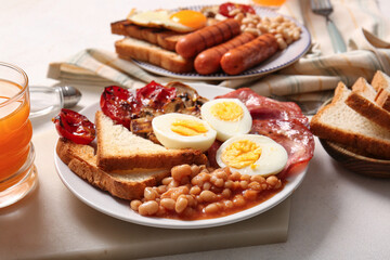 Plates of tasty English breakfast with boiled eggs on light background