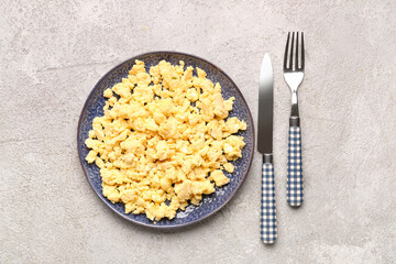 Plate of tasty scrambled eggs on grey background