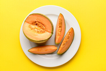 Plate with tasty ripe melon on yellow background
