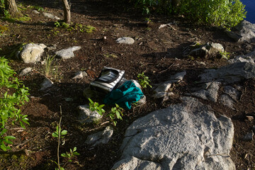 Bag and book on Moss Covered Rocks on Forest Floor