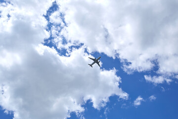 An airplane is in a blue sky with beautiful white clouds. 