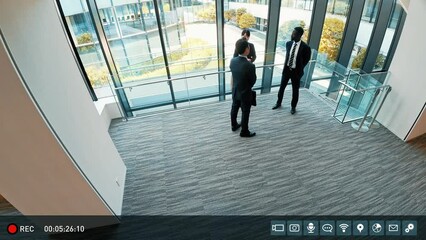 Surveillance camera footage of multinational businesspeople having a conversation inside a building - Powered by Adobe