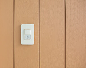 The bell switch is mounted on a brown painted wooden wall.