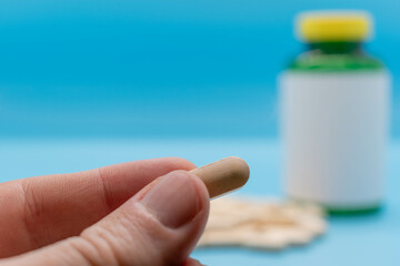 Hand taking a vitamin or medicine tablet, bottle with blank rx out of focus on background pharmacy and health concept copy space