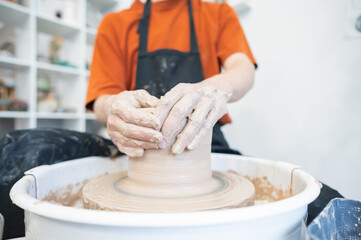 Close-up of a potter's hands working on a pottery wheel. 