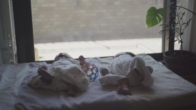 Everyday life of twin children lying on the futon and enjoying toy
