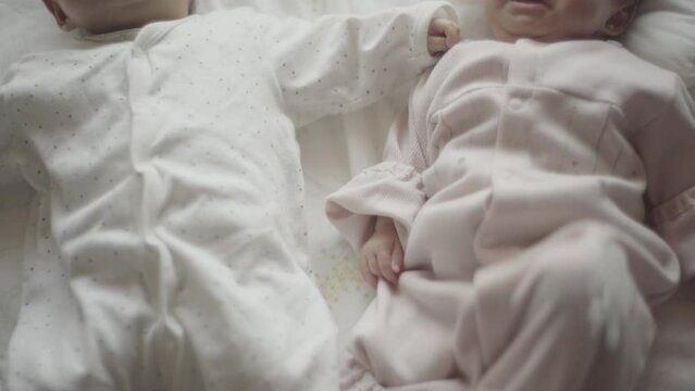 Close twins lying on futon with their hands on top of each other's (4)