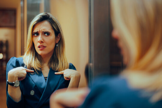 Businesswoman Looking in the Mirror Feeling Insecure. Self-doubting manager having second thoughts suffering from impostor syndrome 
