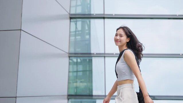 young woman walking in the urban city square looking at camera smile at summer day