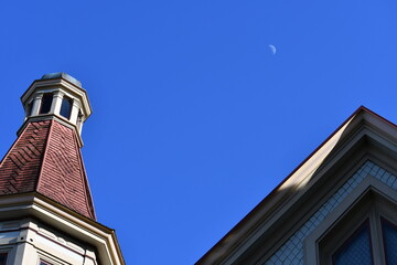 Old Victorian home with daytime moon in distance. 