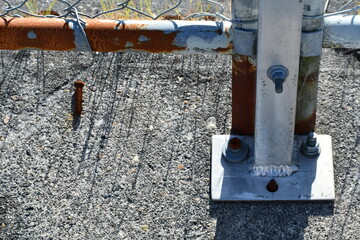 Chain link fence support screwed to concrete.