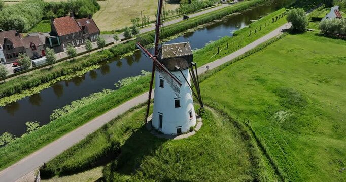 Damme, Belgium, June 2022. Drone orbits the Schellemolen windmill surrounded by lush green fields and Damse Vaart canal.