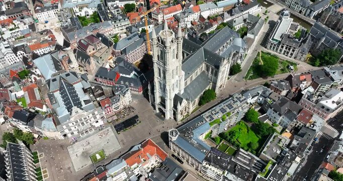 Saint Bavo's Cathedral, East Flanders, Ghent, Flemish Region, Belgium, June 2022. Drone high angle orbit showcases square gathering grounds at base of church.