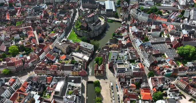 Gravensteen Castle, East Flanders, Ghent, Flemish Region, Belgium, June 2022. Drone descends upon Lieve Canal leading to castle in dense city.
