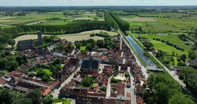 Damme, Belgium, June 2022. Drone orbits the Stadhuis Damme showing historic buildings Damse Vaart canal and lush countryside.