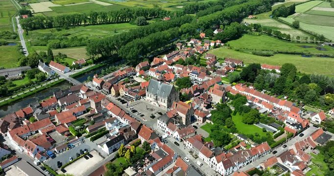 Damme, Belgium, June 2022. Drone orbits the Stadhuis Damme showcasing historic architecture and green landscapes with the Damse Vaart canal in the background.