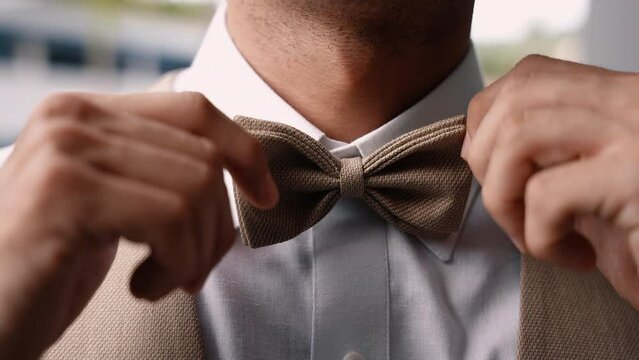 Close up of unrecognizable groom put on brown bow tie - Slow Motion 4K