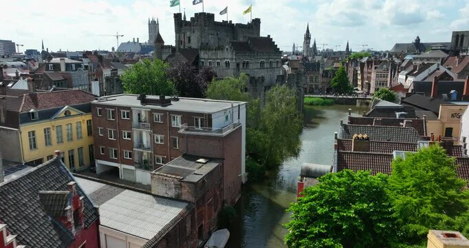 Gravensteen Castle, East Flanders, Ghent, Flemish Region, Belgium, June 2022. Drone pushes along Lieve canal past moat walls of iconic fortress in middle of town.